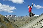 Man jumping down rocky slope with arms raised