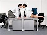 Business couple kissing over desks in office