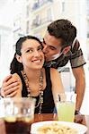 Young couple at sidewalk cafe, man kissing woman, portrait