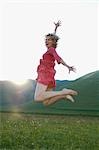 Woman jumping for joy in mountain meadow, side view