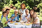 Family sitting at table for lunch in back yard, portrait