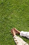 Mittleren Alter paar liegend auf Gras, niedrige Abschnitt Nahaufnahme von barfuss