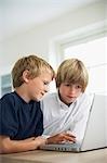 Two brothers using laptop on table at home