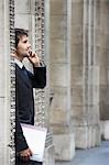 Businessman standing by colonnade pillars talking on cell phone