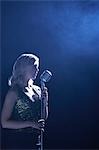 Femme chantant dans un micro en place enfumée, vue latérale