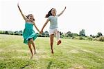 Girls Running and jumping Hand in Hand through field