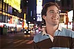 Young man standing in Times Square New York at night