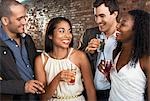 Two couples holding drinks, standing in bar