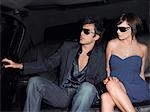 Junges Paar im Rücksitz der Limousine Abendkleid und Sonnenbrillen tragen