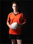 Rugby player standing holding ball, portrait