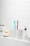Toothbrushes face to face on shelf in white bathroom