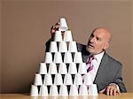 Businessman Building Pyramid of Cups on table