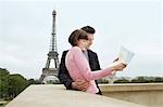 France, Paris, Couple reading map on balcony in front of Eiffel Tower