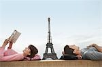 Couple lying on ledge of the Trocadero with Eiffel Tower viewed in the background