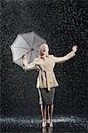 Woman standing in overcoat, holding umbrella, singing in the rain