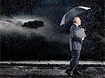 Homme d'affaires marche sous la pluie sous le parasol, vue latérale