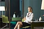 Businesswoman sitting in office, smiling, portrait