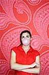 Teenaged girl blowing bubble against pink and red patterned wallpaper