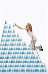 Woman kneeling on ladder to stack plastic cups into pyramid against white background