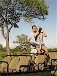 Couple on safari, standing in jeep, woman looking through binoculars