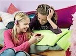 Smiling girls in bedroom looking at mobile phone