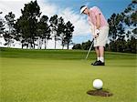 Golfer putting, low angle view