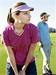 Two young golfers on course, focus on woman