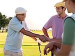 Yong golfers shaking hands on course