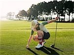 Young female golfer placing ball on tee