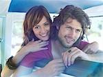 Young couple leaning over back of seat in van