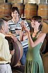 Three people wine-tasting beside wine casks