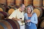 Man and woman with wine-glass aside wine casks