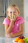 Girl eating apple in kitchen