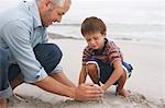 Vater und Sohn (5-6) spielen im Sand am Strand