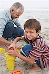 Father and son (5-6) playing in sand on beach