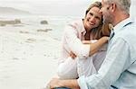 Couple sitting on beach, smiling