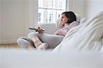 Woman lying on sofa, watching television