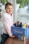 Girl (10-12) putting empty vessels into recycling container, smiling, side view