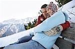 Couple embracing, assis sur un banc sur flanc de colline, vue latérale