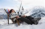 Skier resting on deckchair in mountains