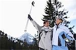 Couple laughing, standing on ski slope, low angle view