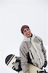 Homme debout sur la neige, transportant snowboard, portrait