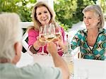 Three people toasting with wine glasses, sitting at verandah table