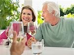 Three people sitting at verandah, holding wine glasses