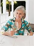 Frau hält Glas Wein am Tisch der Veranda, Porträt