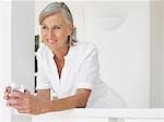 Woman holding glass of water leaning on verandah balustrade, portrait