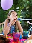 Young girl (10-12) blowing party puffer at birthday party