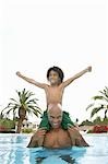 Father carrying son on shoulders son (5-6 years) standing in swimming pool