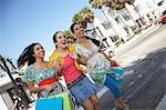 Three teenage girls (16-17) carrying shopping bags, crossing street