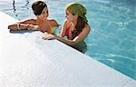 Two teenage girls (16-17) standing in swimming pool, elevated view